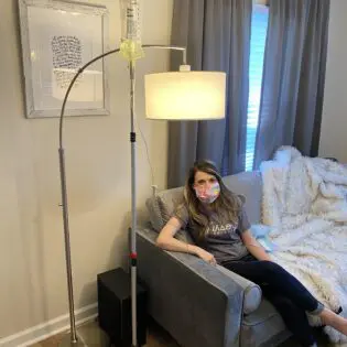 A woman sitting on the couch in front of a lamp.
