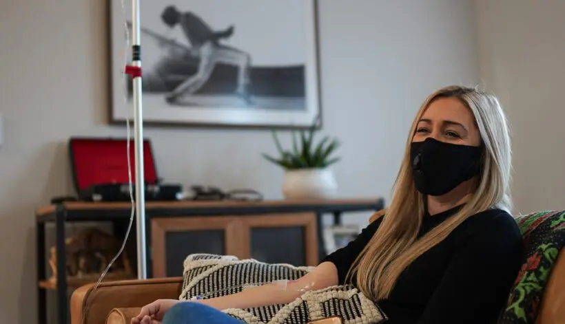 A woman sitting on the couch wearing a mask.
